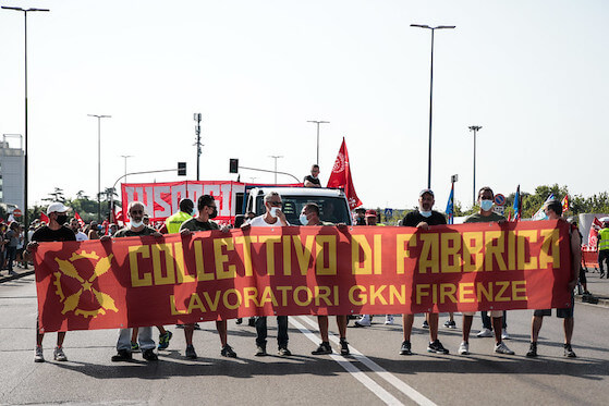 Foto von Arbeiter*innen des #insorgiamo einer Fabrik die ein Transparent halten auf dem steht: "collectivo di fabrica, lavoratori gkn firenze"